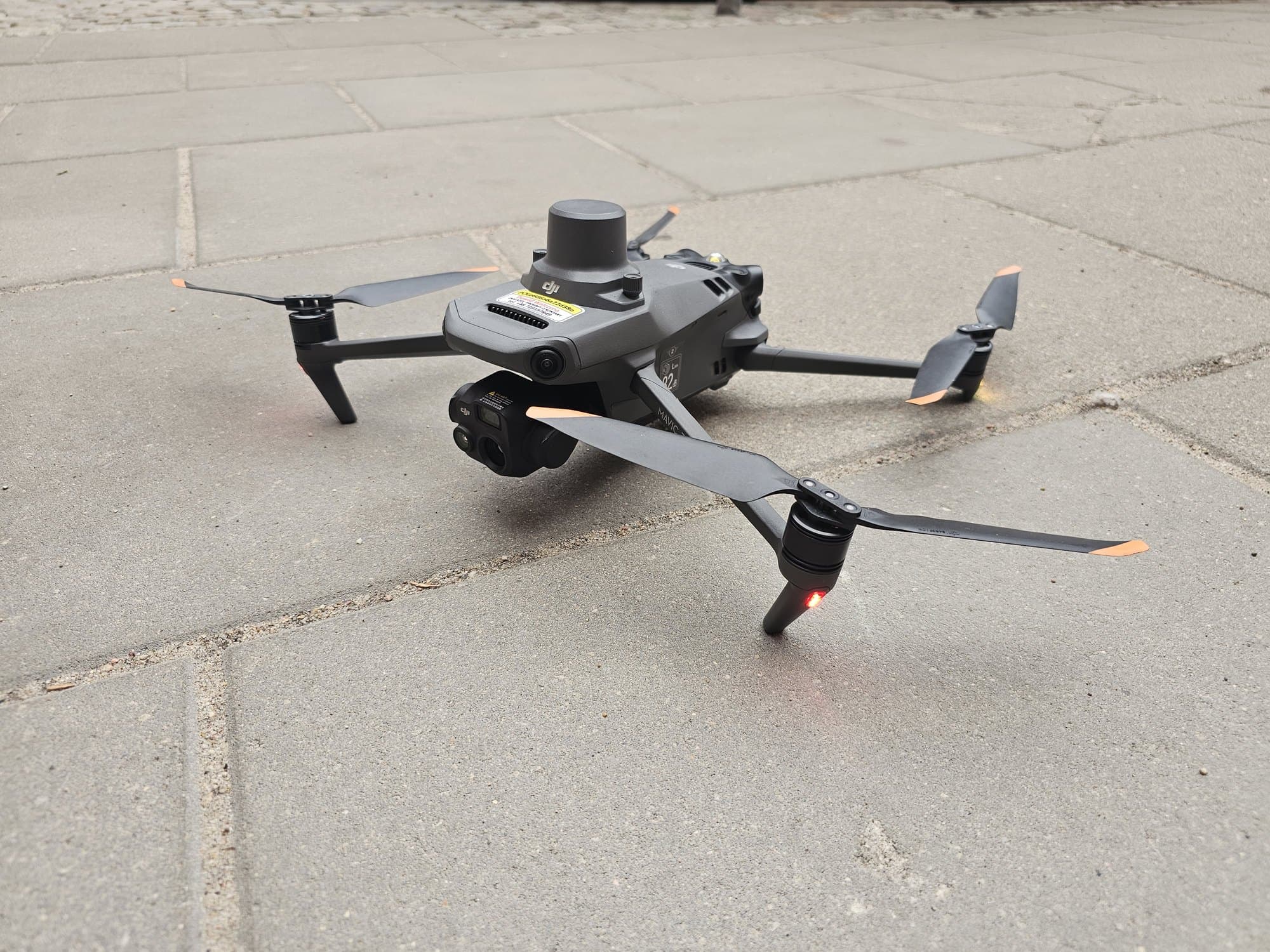 Dron na płycie startowej, śmigła rozłożone.