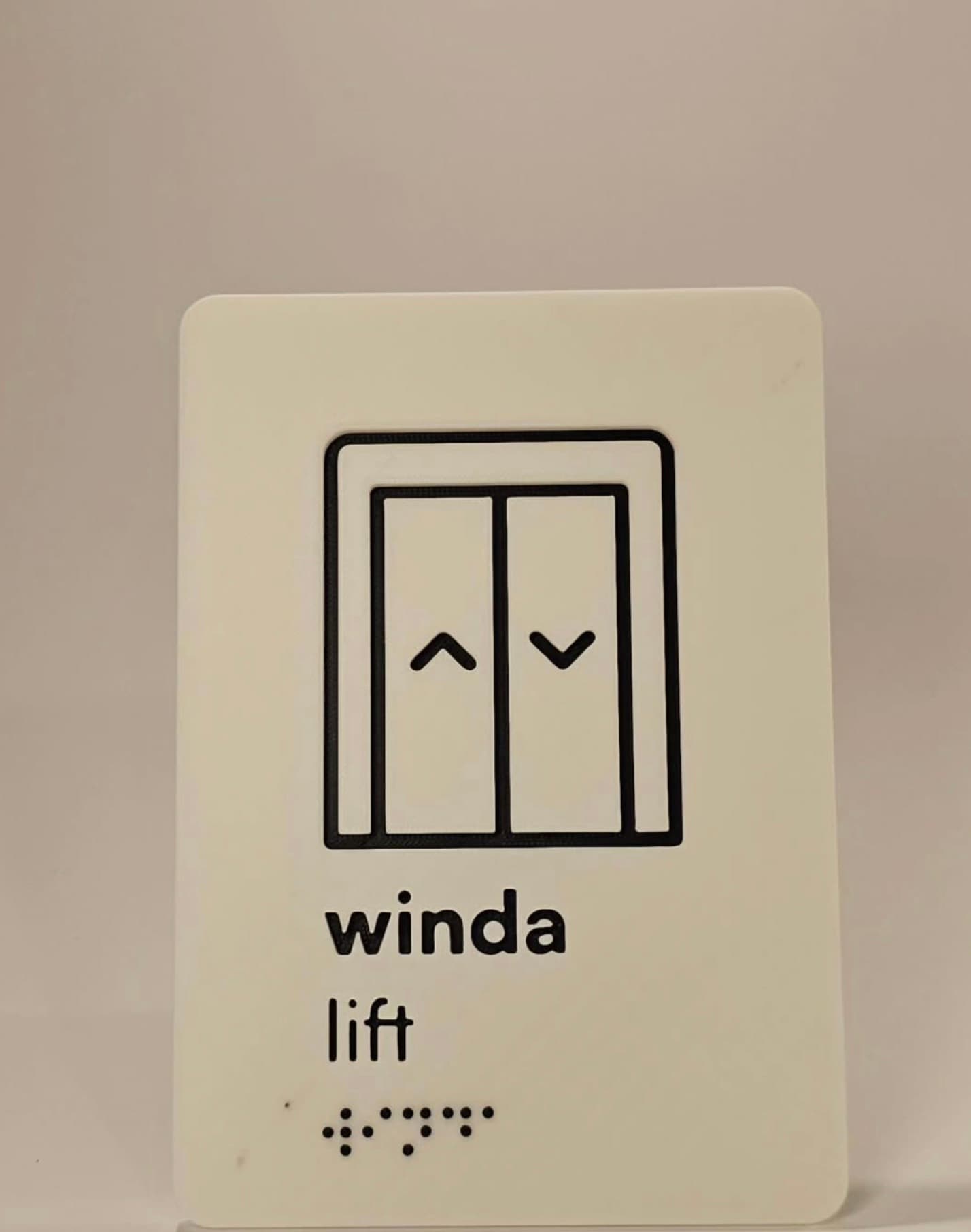Tabliczka windy z piktogramem i brajlem z tego samego zestawu oznaczen
