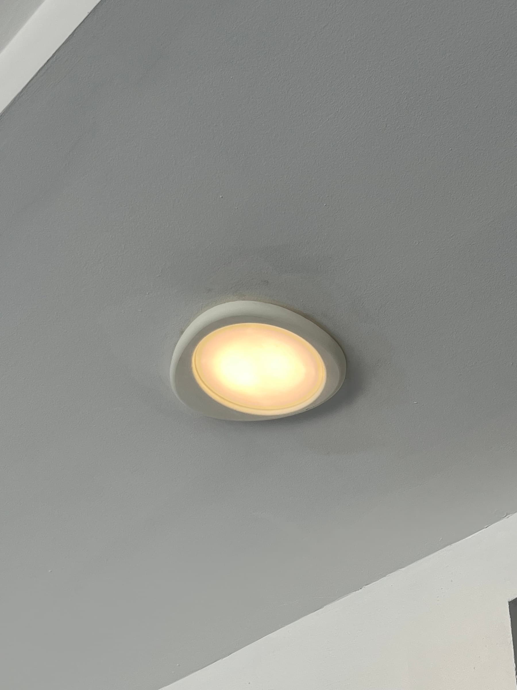 Zapalona lampa sufitowa rzucająca ciepłe światło na biały sufit.