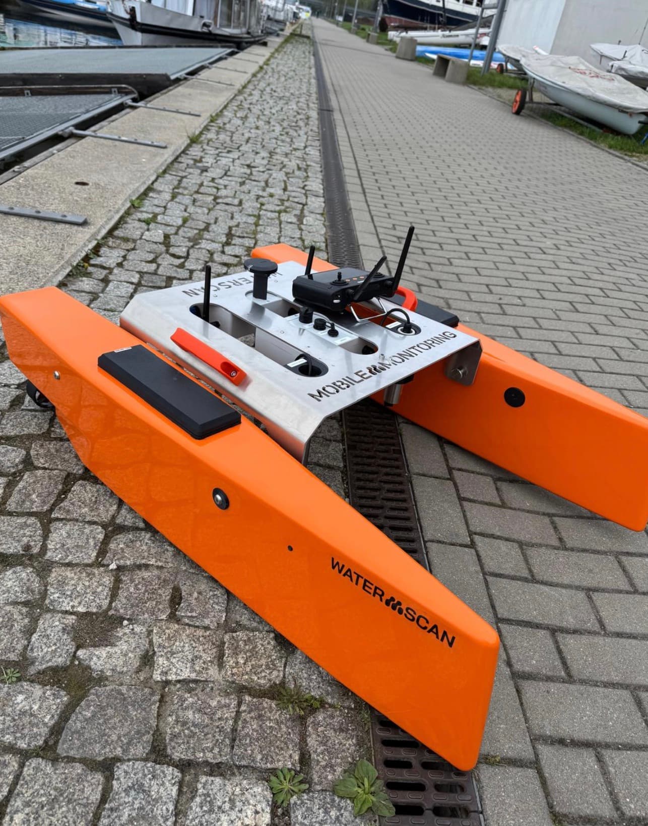 Dron wodny WATER SCAN na nabrzeżu, widoczny moduł elektroniki i oznakowanie Mobile Monitoring.