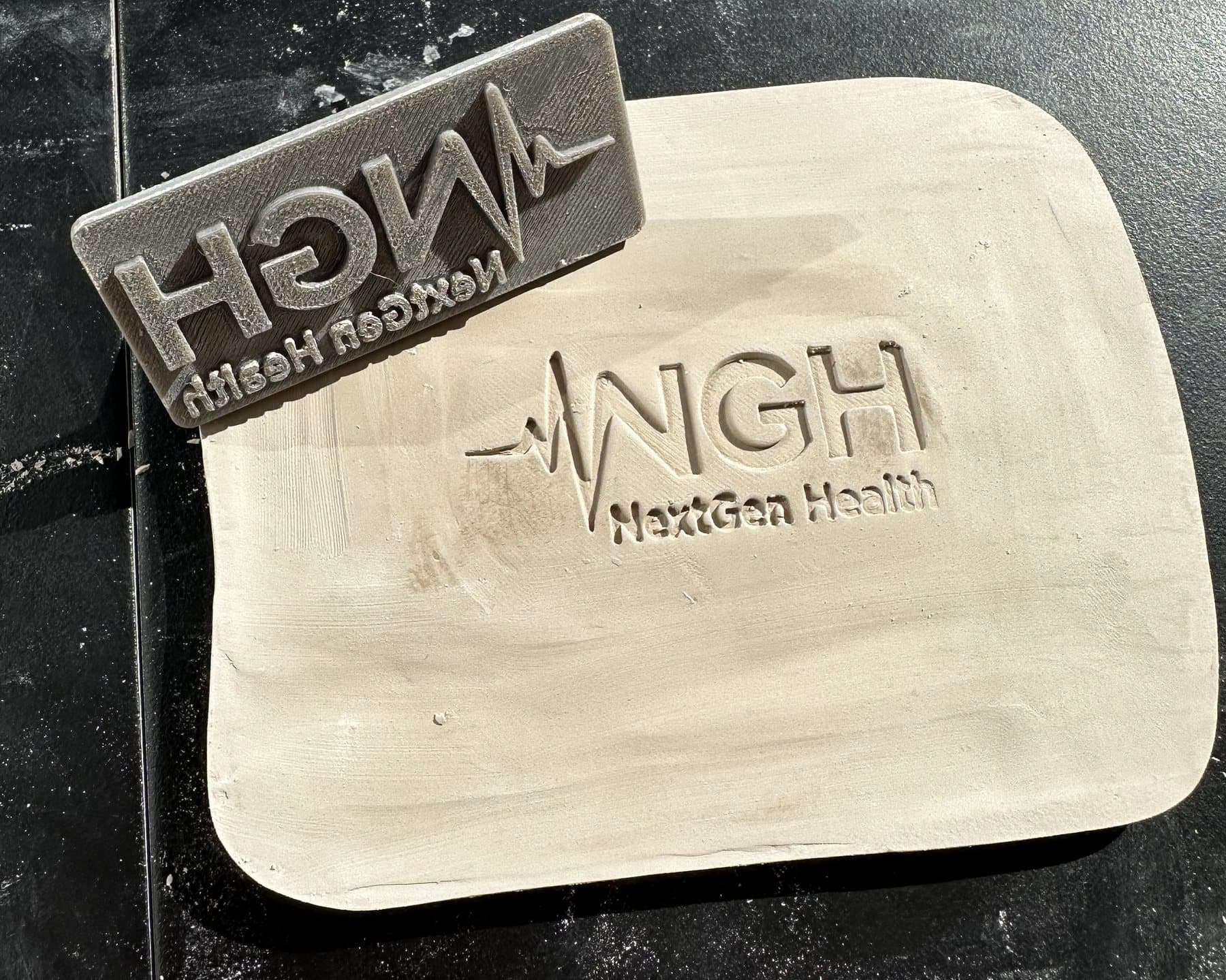 Stempel obok świeżego odcisku w płacie gliny na ceramiczną wizytówkę.