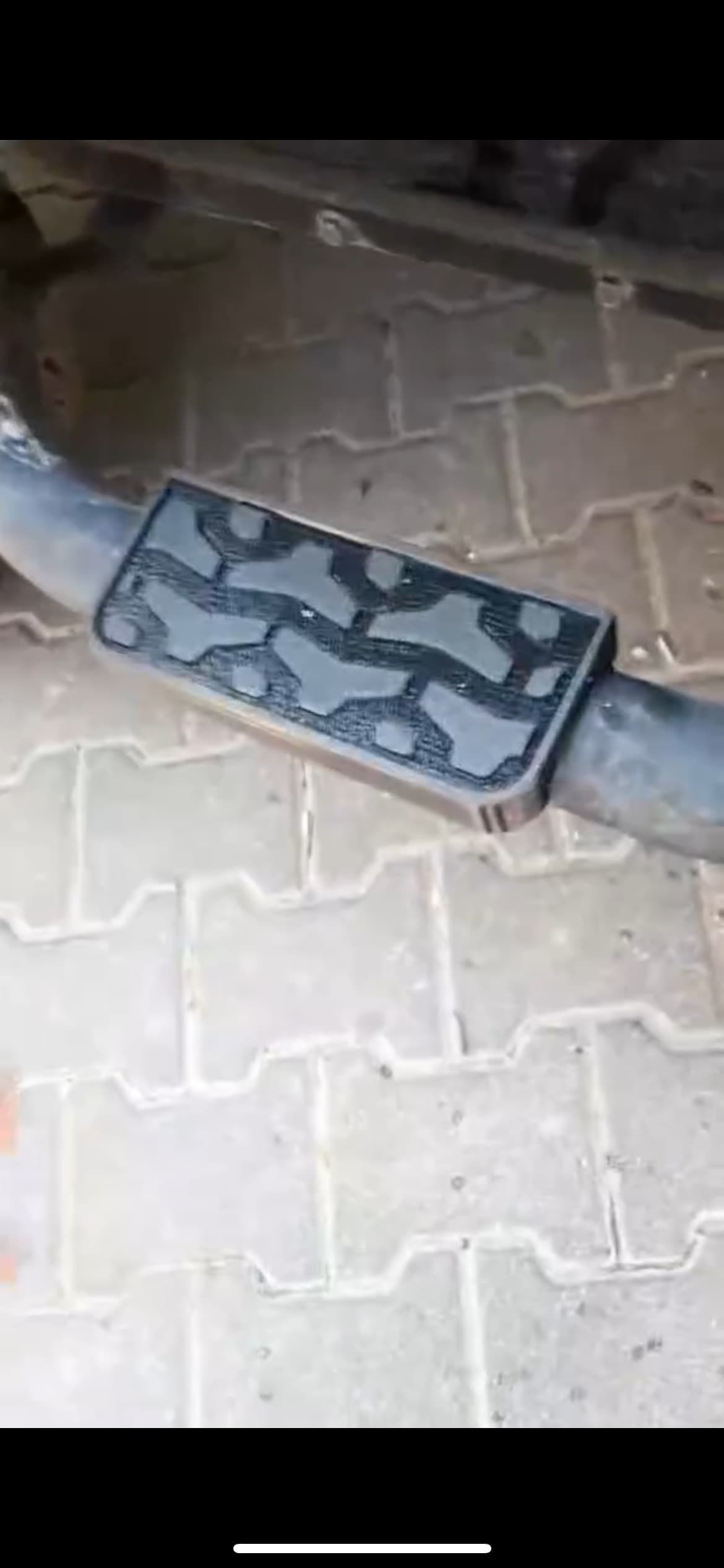 Gotowy stopień zamontowany na oryginalnej okrągłej belce bocznej, widok z góry na kostce brukowej.